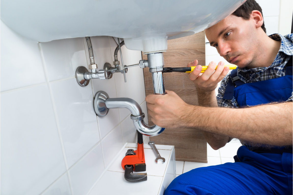 Plumber repairing pipework under a sink