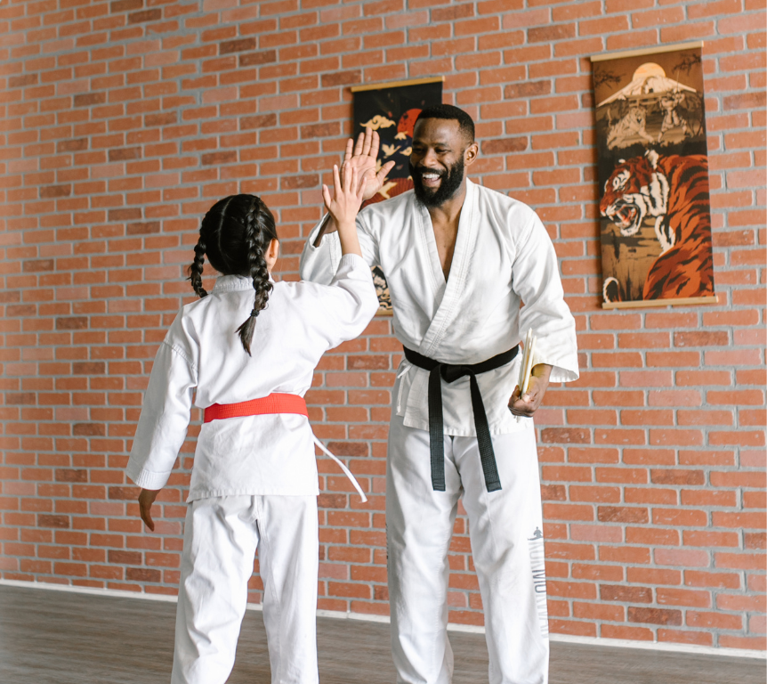 Martial arts coach high-fiving a student